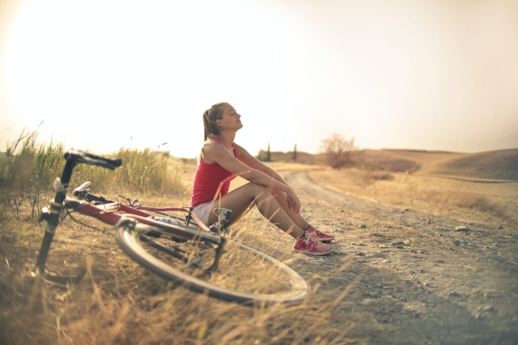 mujer sentada descansando bici disfrutando del paisaje